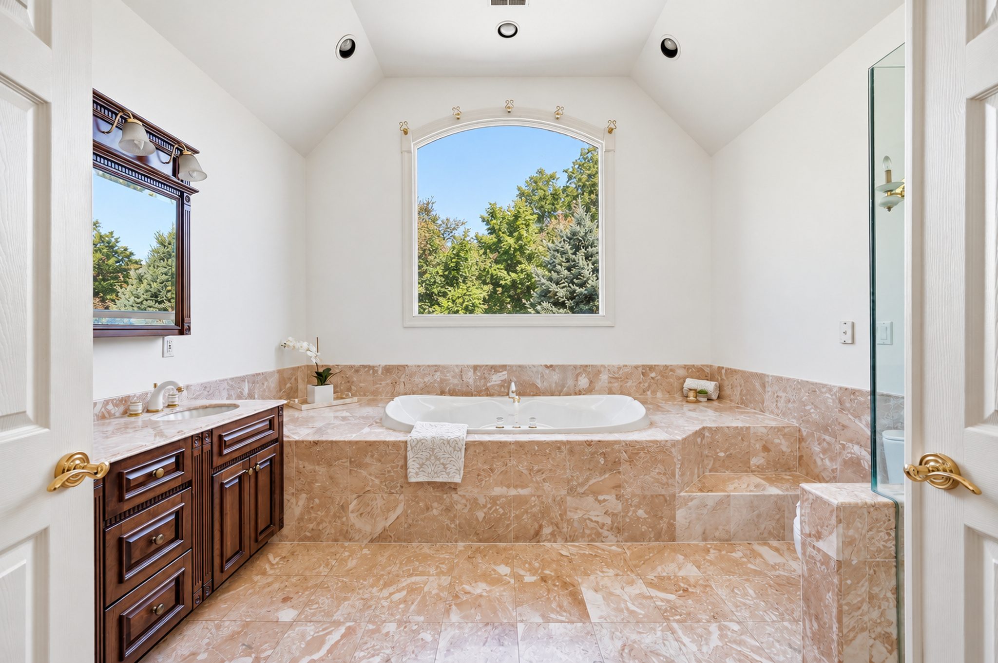 Spa inspired primary bath with soaking tub beneath an arched window at 54 Burnet Hill Road, Livingston