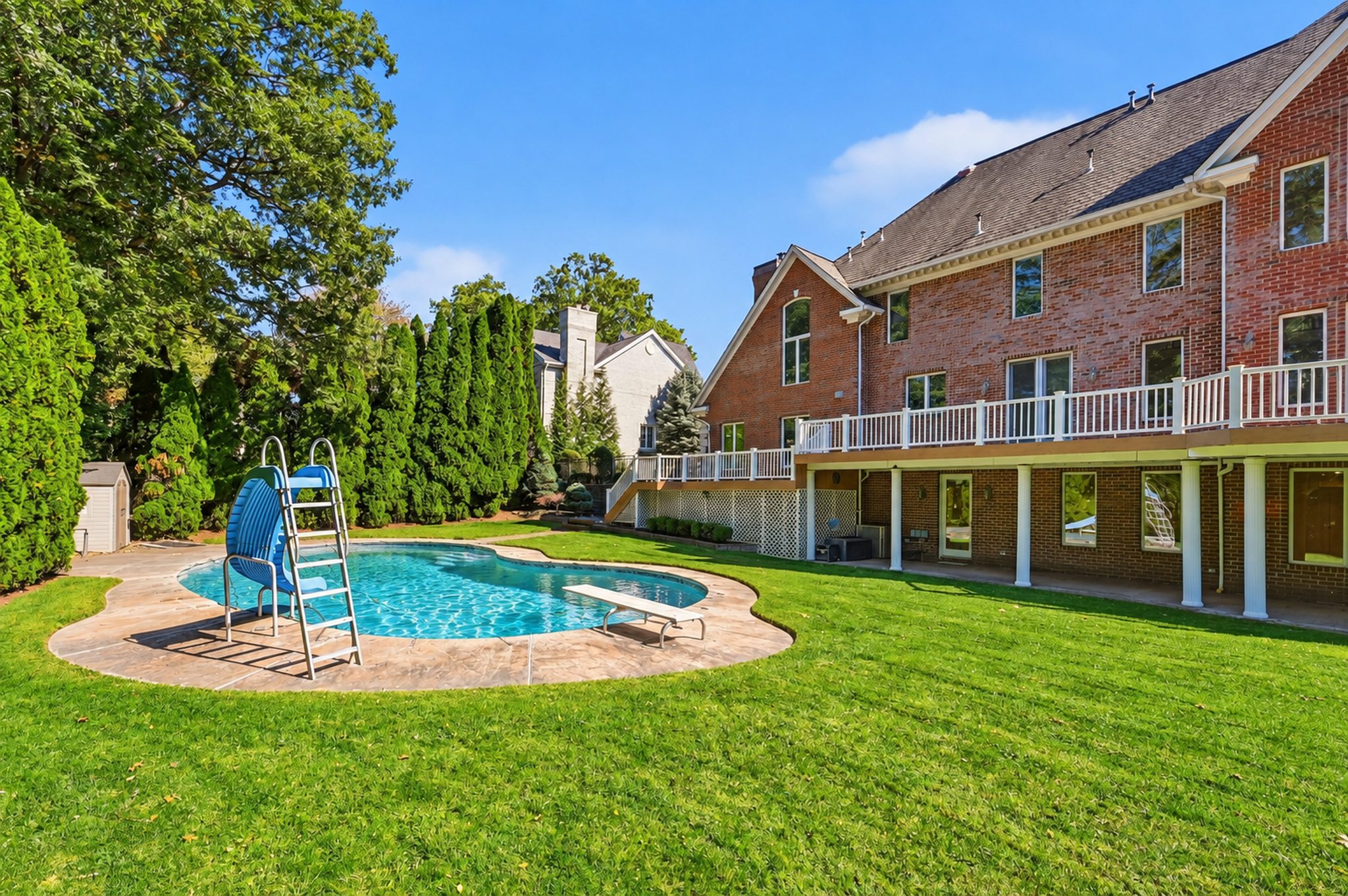 Pool with slide set against evergreen privacy plantings at 54 Burnet Hill Road, Livingston